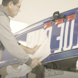 Man installing "Blue Bus" lettering on the back of a bus